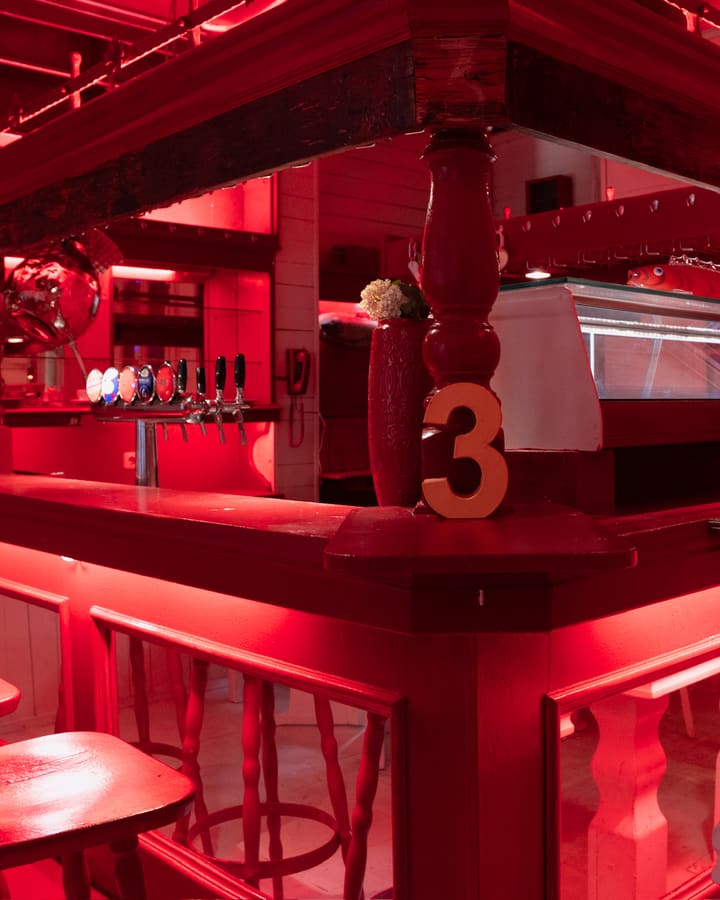 Bar mit Hockern und Kühlvitrine in rotem Licht