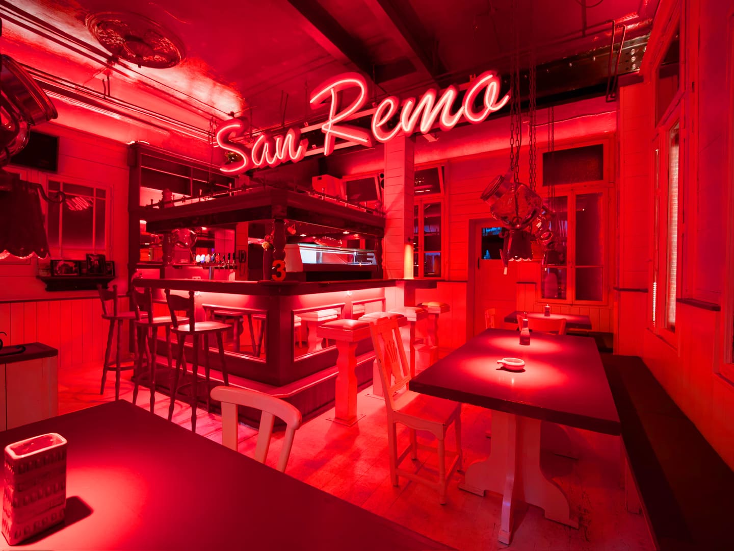Gastraum des San Remo in rotem Licht mit Bar und leuchtendem Neonschriftzug „San Remo“