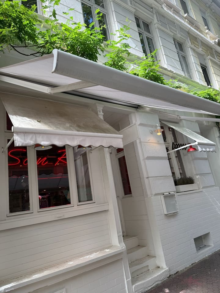Eingang des San Remo mit Markisen und Neonschrift im Fenster